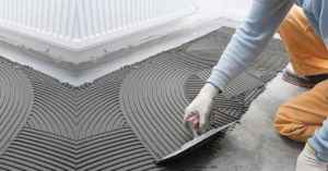 Tile adhesive being applied with a notched trowel for floor and wall tile installation