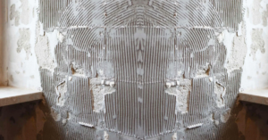 Removing tile adhesive from floor and wall using scraper and professional tools